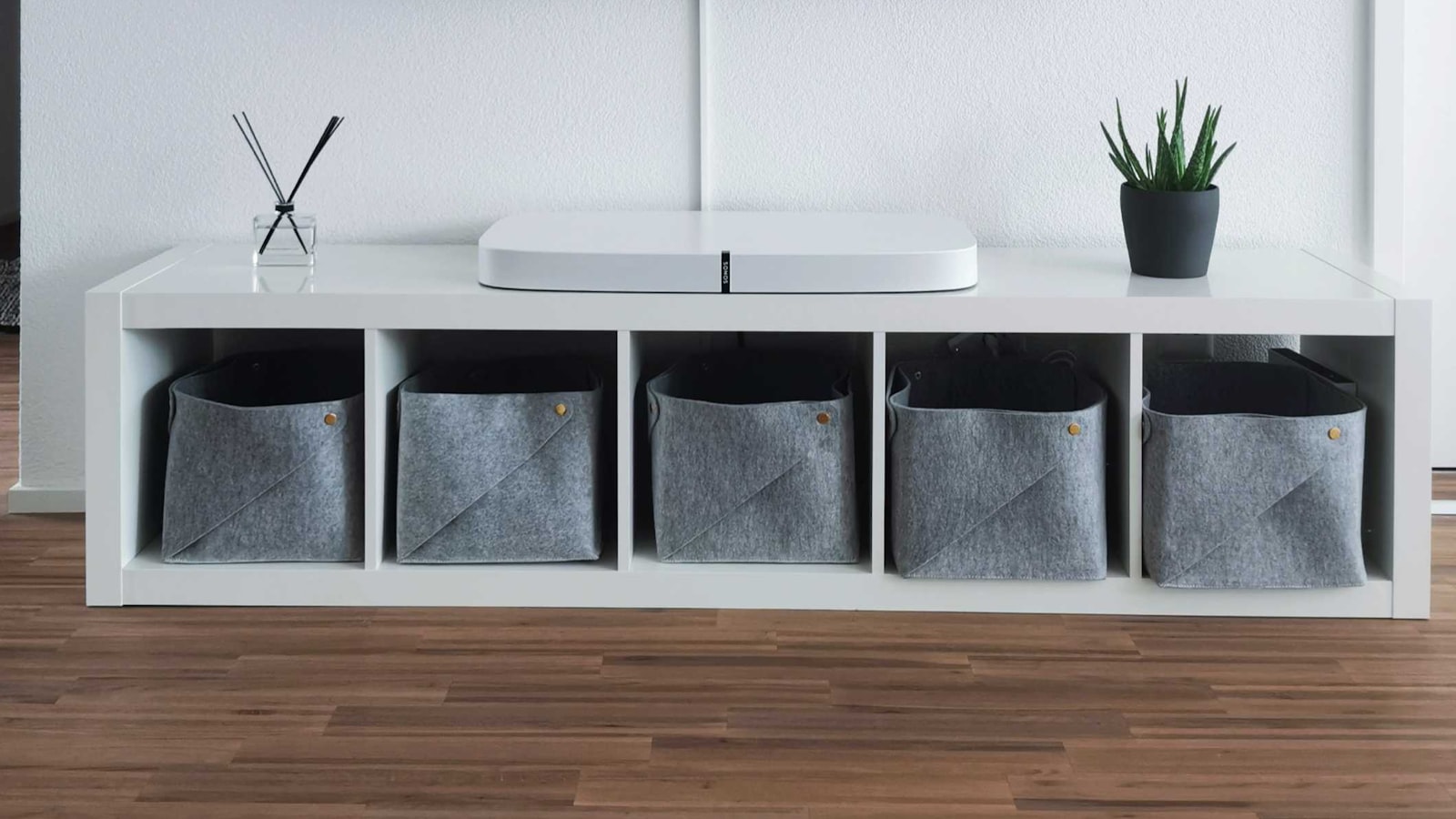 A voice-assistant smart speaker on a shelf in a living room.